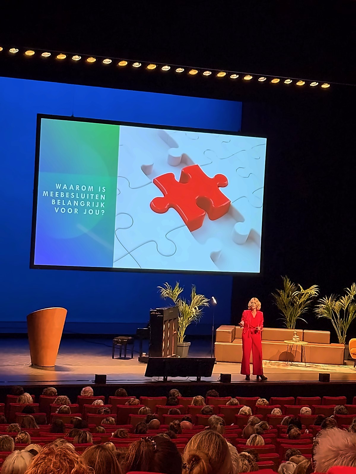 Anke Siegers op een groot podium voor een volle zaal